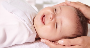 Bébé souriant se faisant caresser la tête